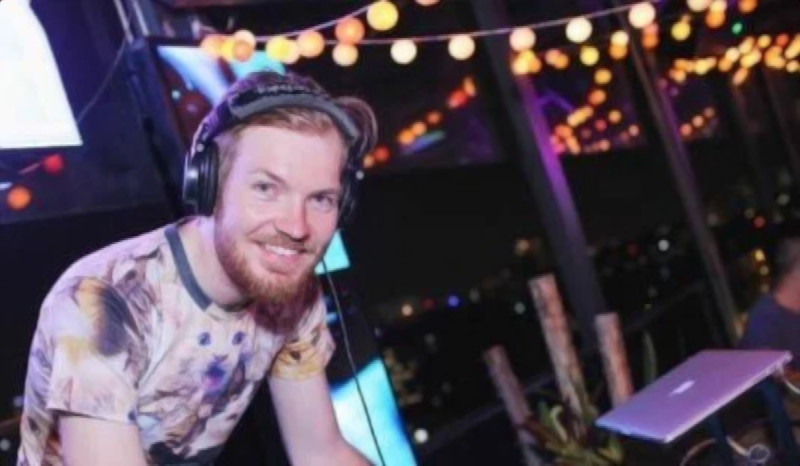 British DJ and Producer Coh-hul smiling at camera wearing headphones whilst performing as a DJ.