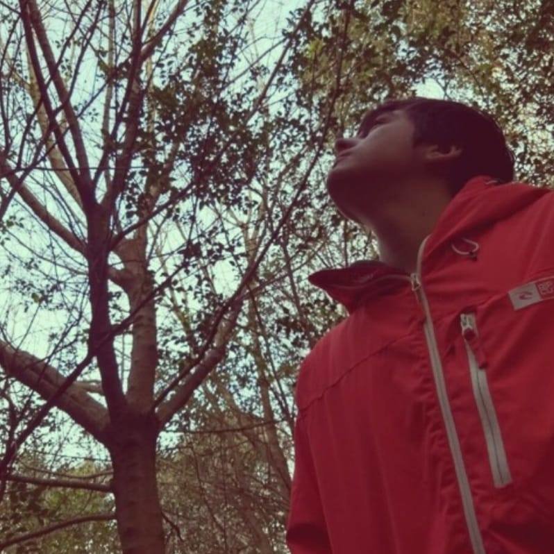 Argentinian DJ and producer Ocean Bloom standing in Forest looking up at trees