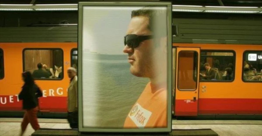 Portuguese DJ Joshuas face on an advertising board inside a train staion will passengers getting on and off the train, colour image