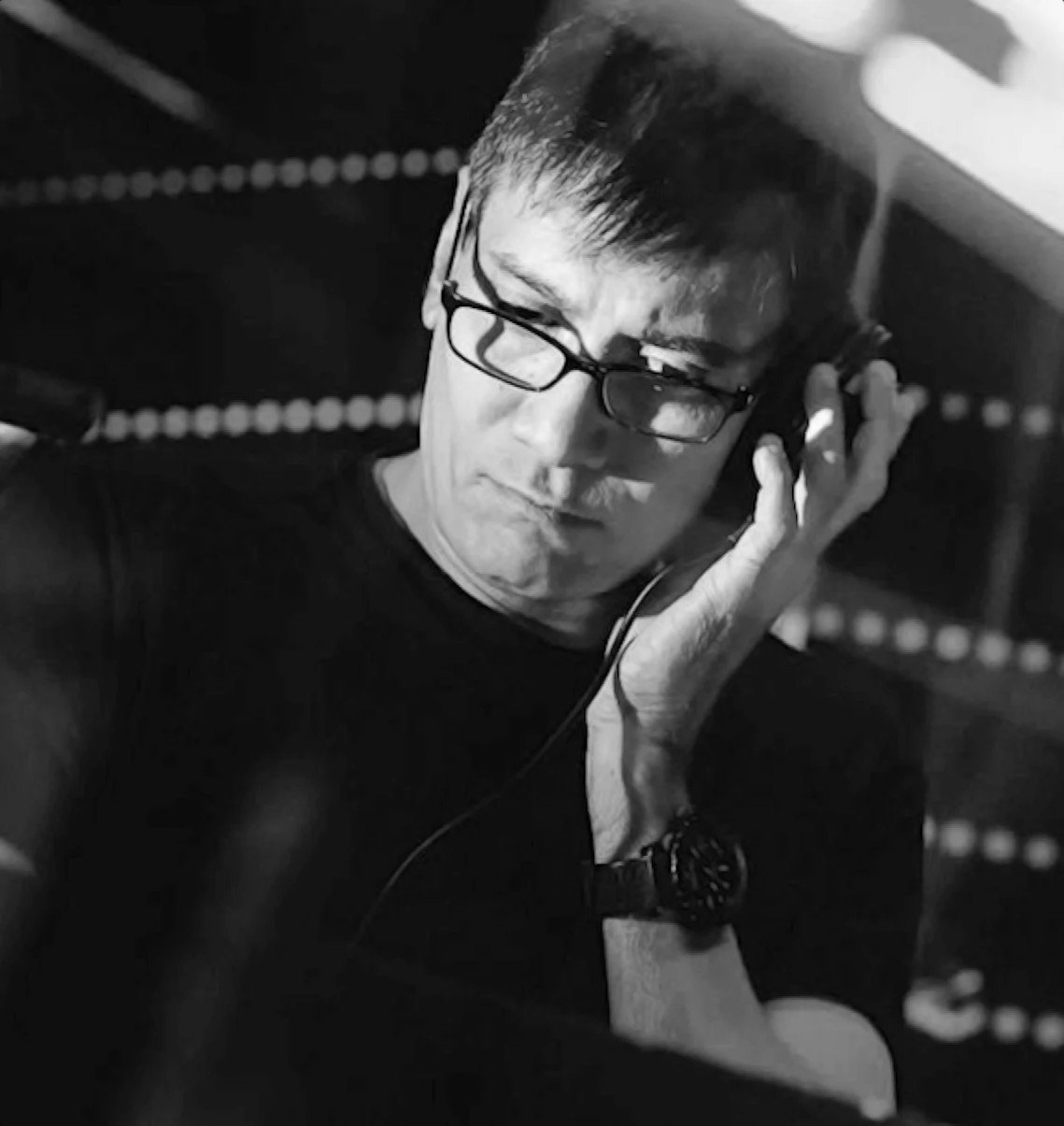 Singaporean DJ and producer Brendon P performing at an event with his left hand on the cup of the headphone, black and white image.