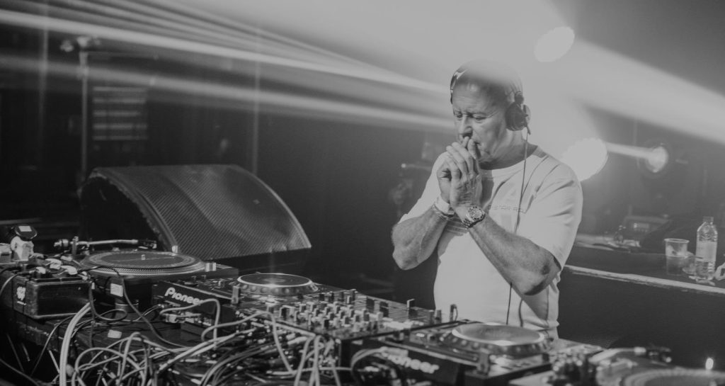 DJ magazine Top 100 DJ and Producer Graham Gold standing with hands together over Technics Dj Equipment at Peach London, black and white image.