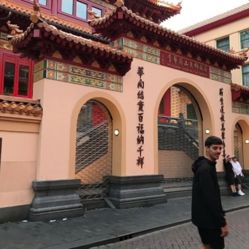 Argentinian DJ and producer Agustin Giri walking outside a Buddhist temple in Asia, colour image.