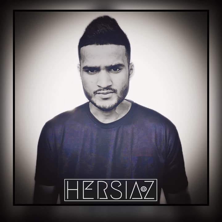 Sri Lankan DJ Hersiaz Hazi looking at the camera in black and white shot with his logo beneath his chest and a blue tinted T shirt.