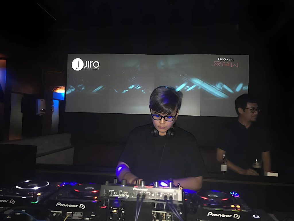 Malaysian DJ and producer Terence C performignat Jiro whilst looking down at the mixer, colour image.