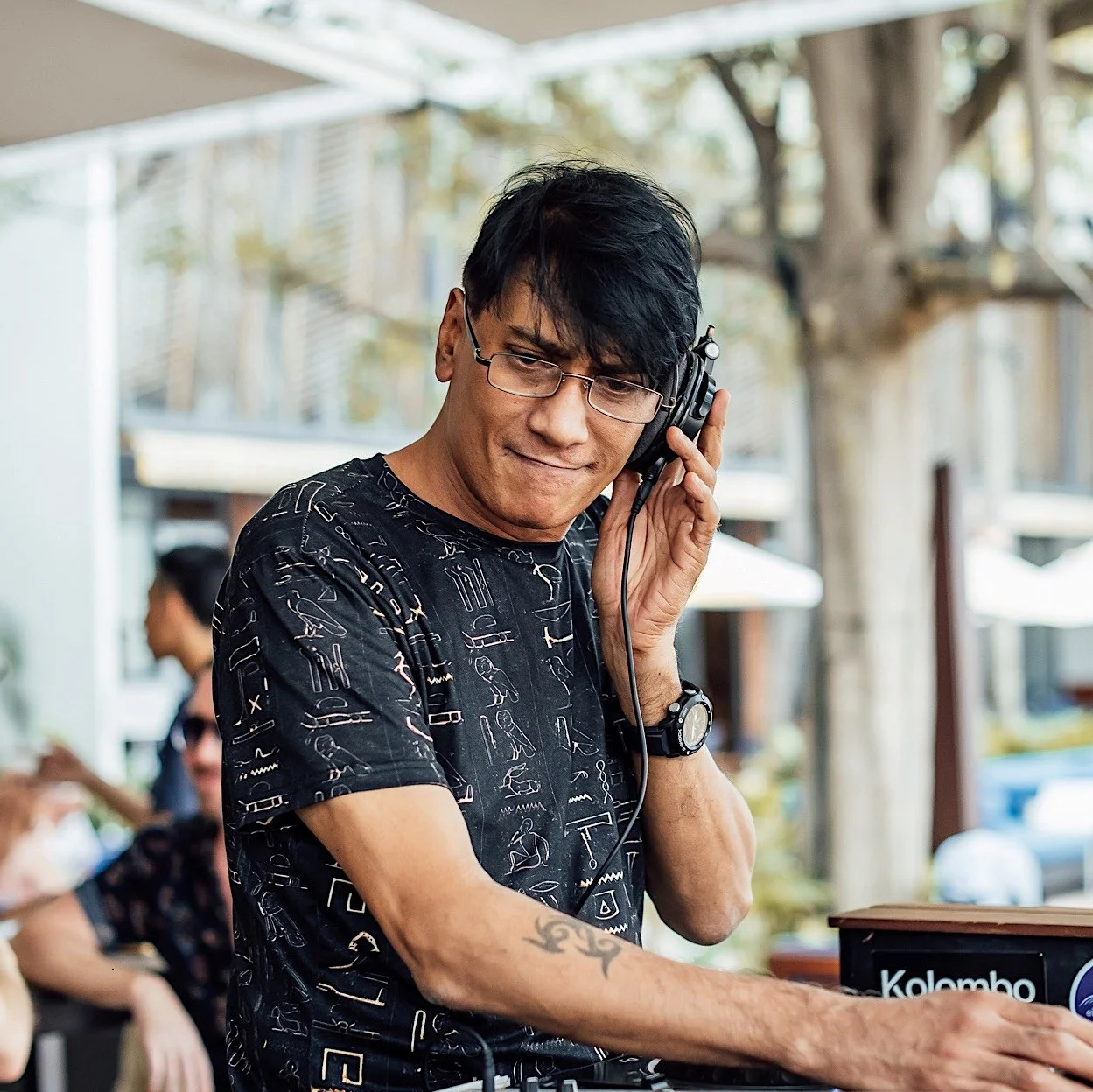 Singaporean DJ and producer Brendon P holding his headphone on his left ear at an outdoor event, colour image.
