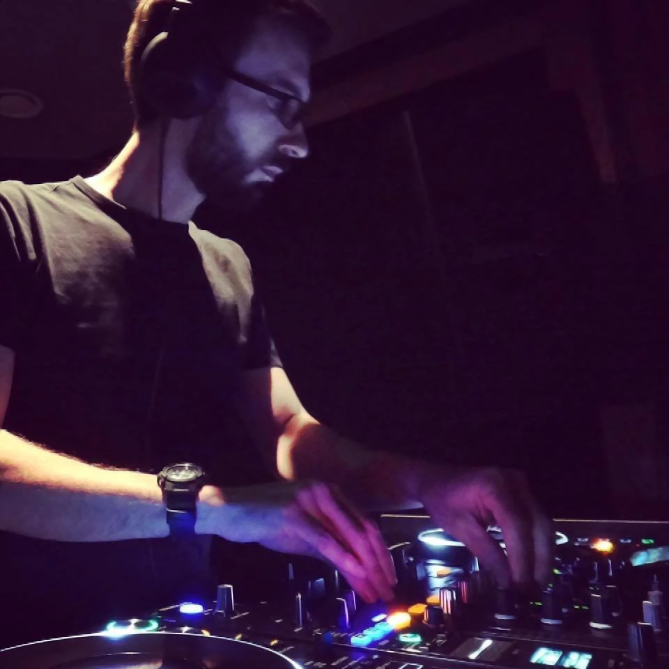 British DJ and producer D-PET performing as a DJ at an event, colour image.