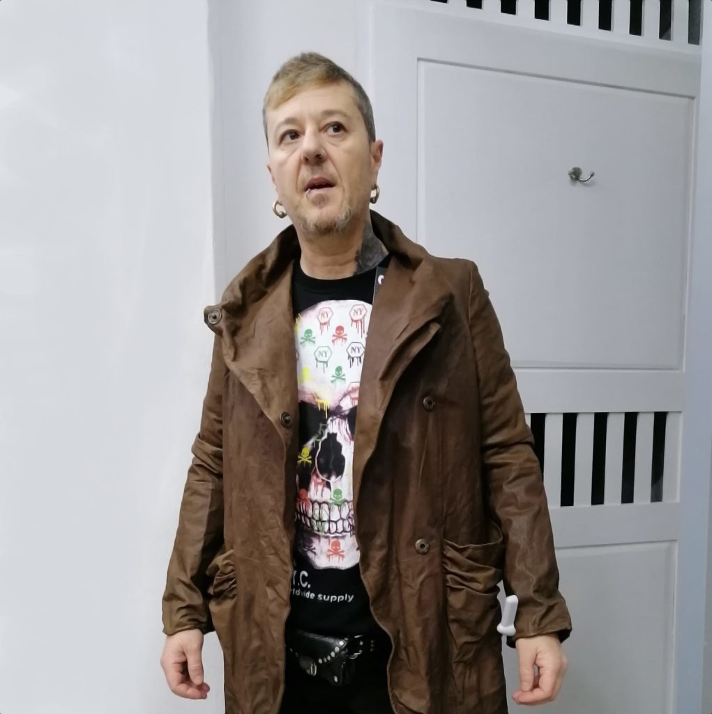 Italian DJ and producer El Brujo standing wearing a coat, colour image.