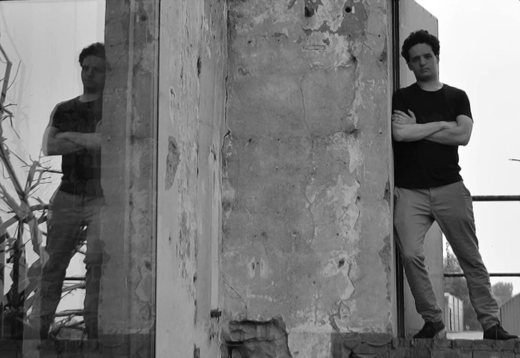 Italian DJ and producer pulsɘs leaning against a piece of concrete, black and white image.