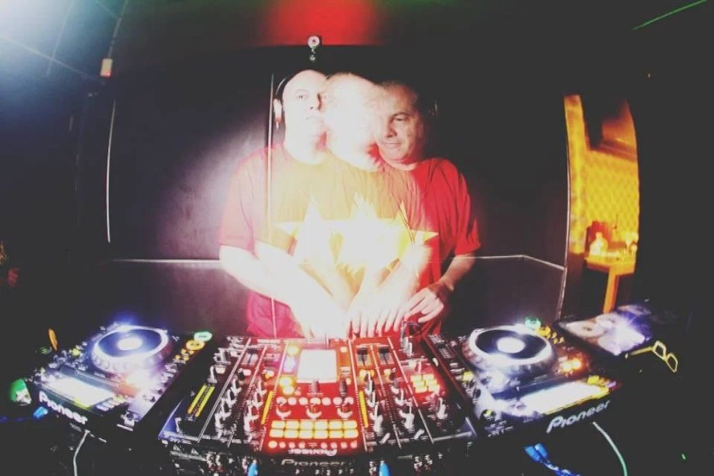 Italian DJ and producer Marco Mei performing at an event, his upper body blurred, colour image.