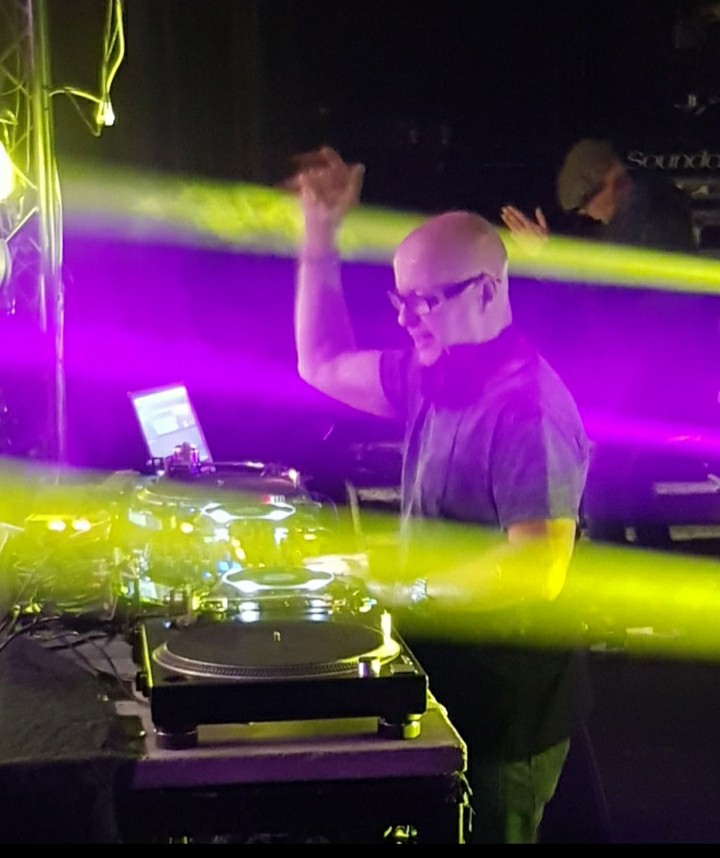 British DJ and producer Graham Gold performing at an event with his right hand raised, colour image.