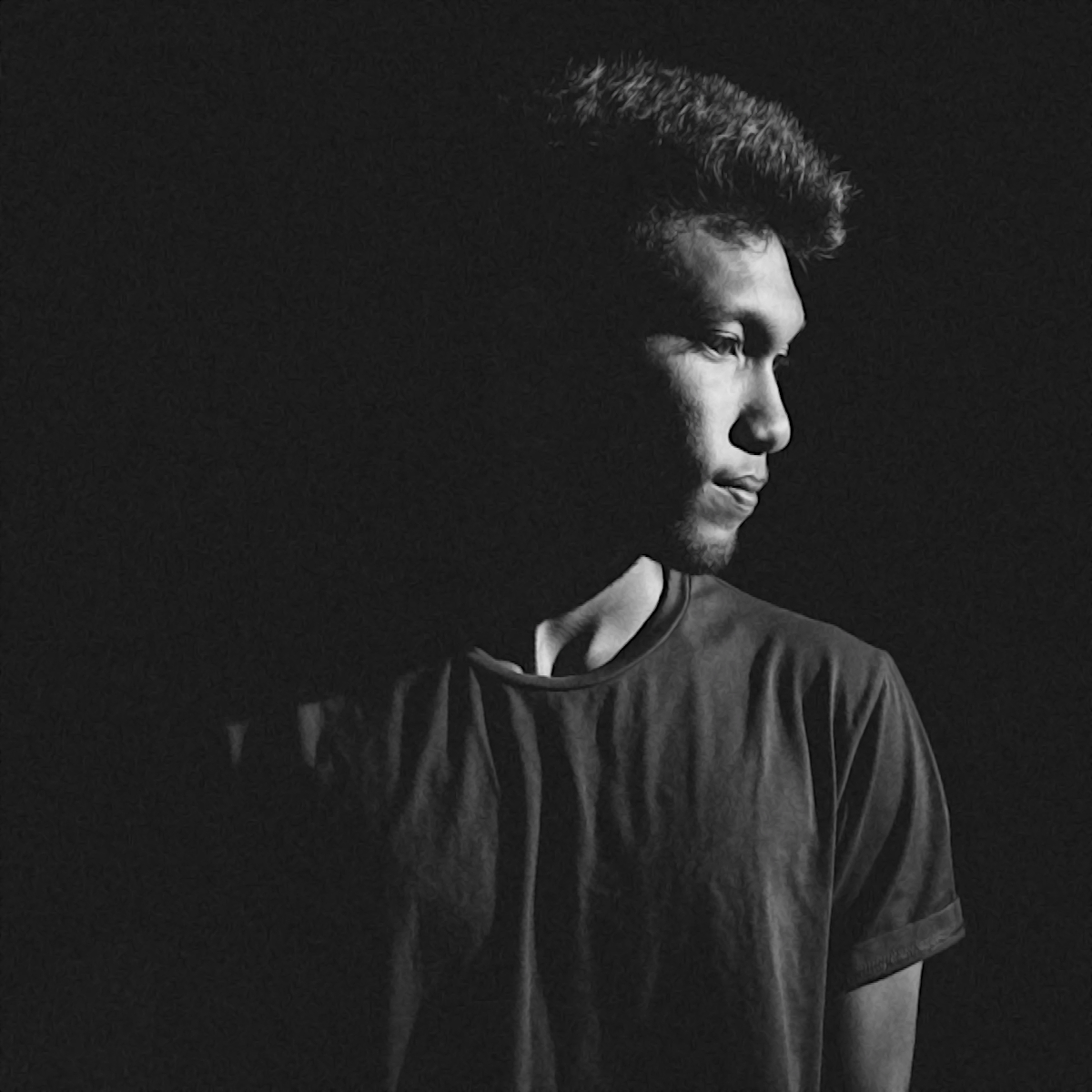 Sri Lankan DJ and producer ALPHA21 in a studio photo looking over his left shoulder, black and white image.