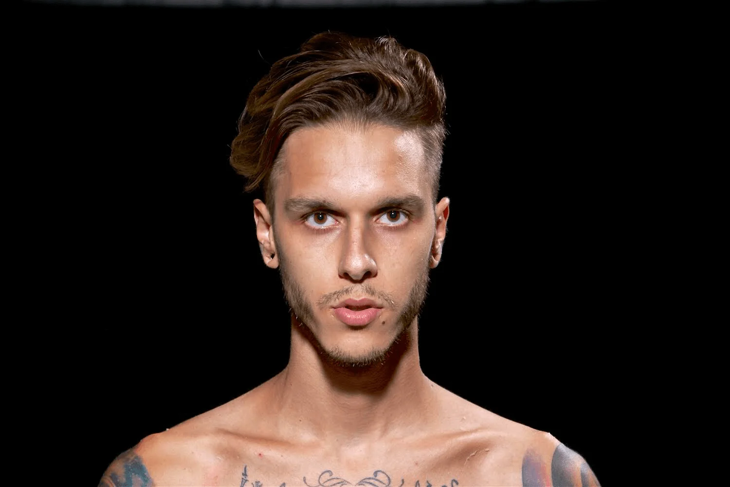 Russian DJ and producer Ernest Kalinin standing bare chested staring at camera, colour image.