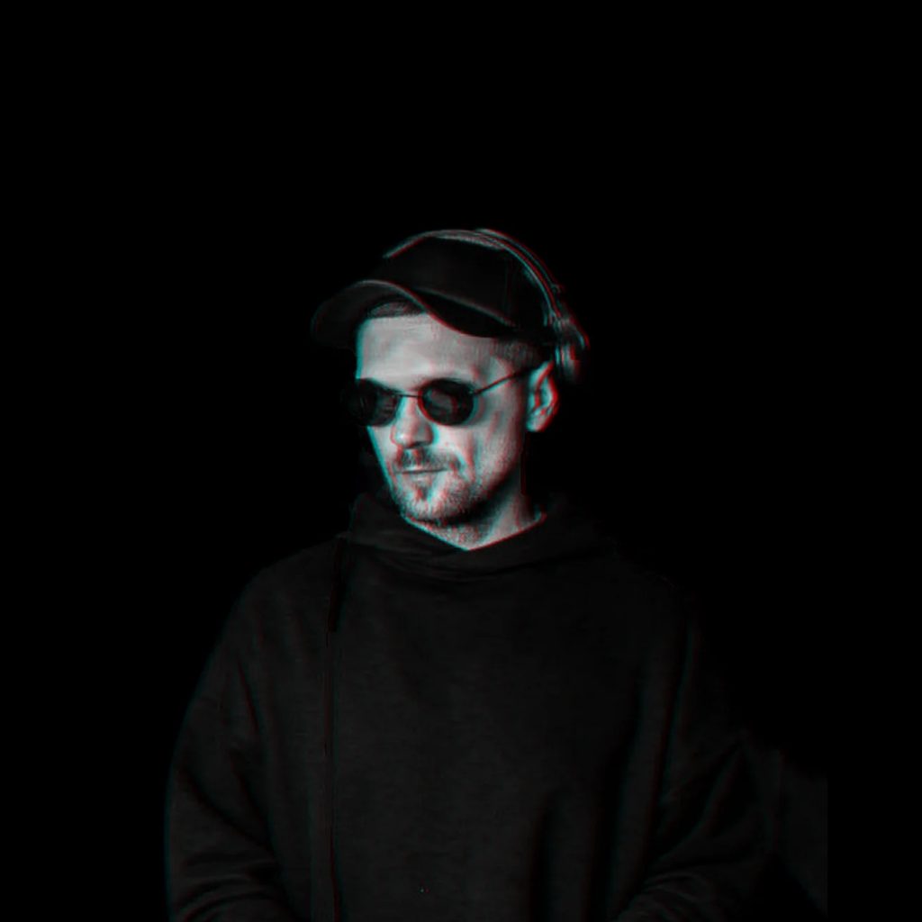 Belarusian DJ Igor Hush Standing in dark room wearing sunglasses, black and white image.
