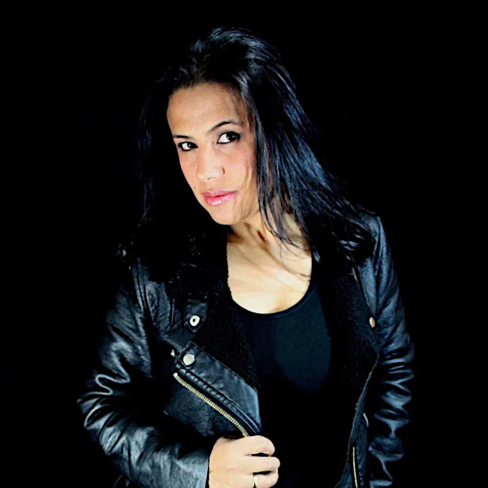 Colombian DJ and producer Katalina standing in studio wearing a leather jacket, colour image.