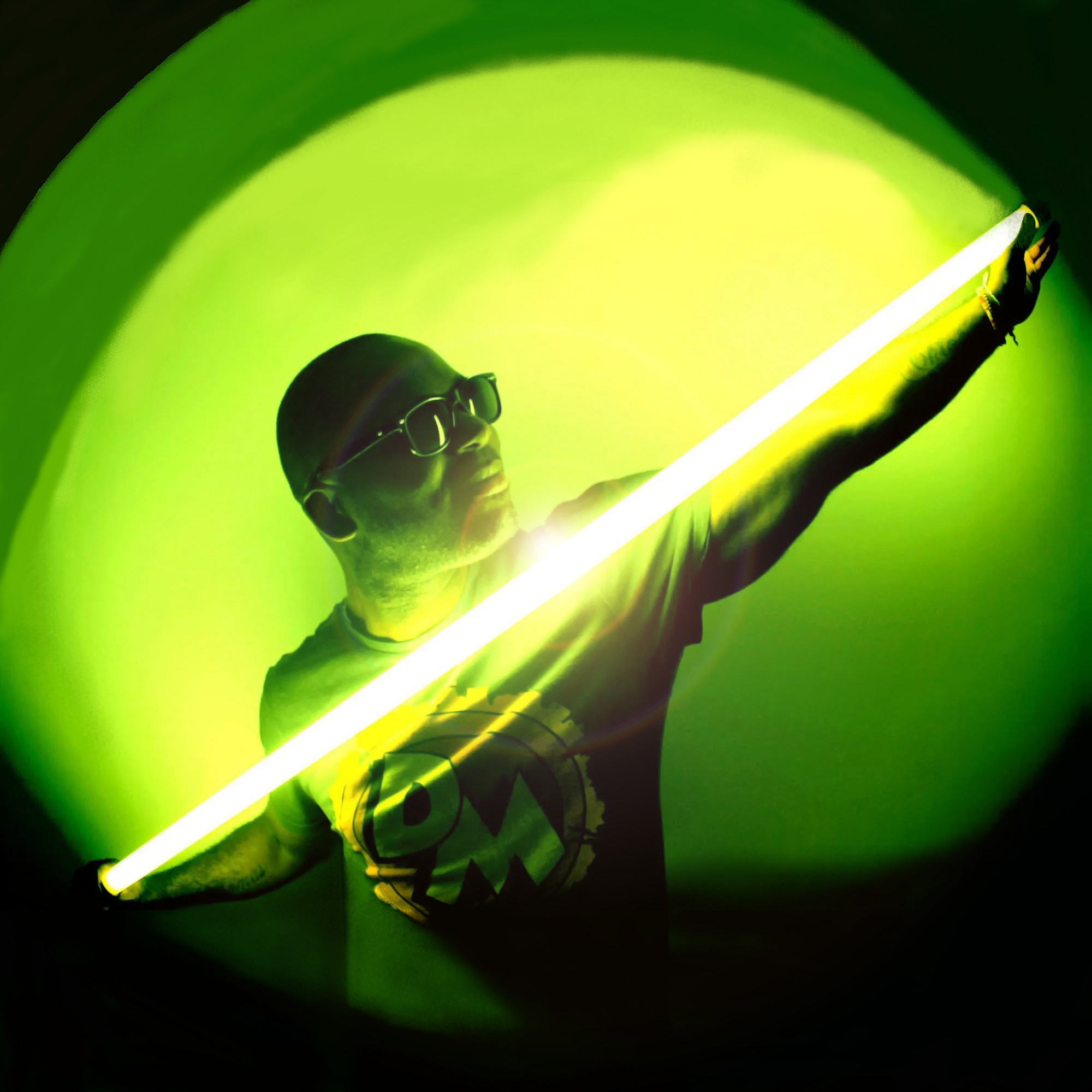 French dJ, producer, and label owner DJ Marcmite holding a light saber light green in colour in a sphere of light, colour image.