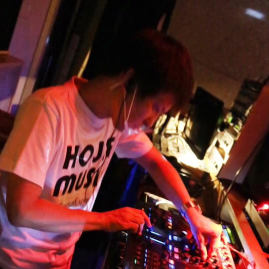Japanese DJ and Producer Takamasa Owaki performing on a Traktor controller, colour image.