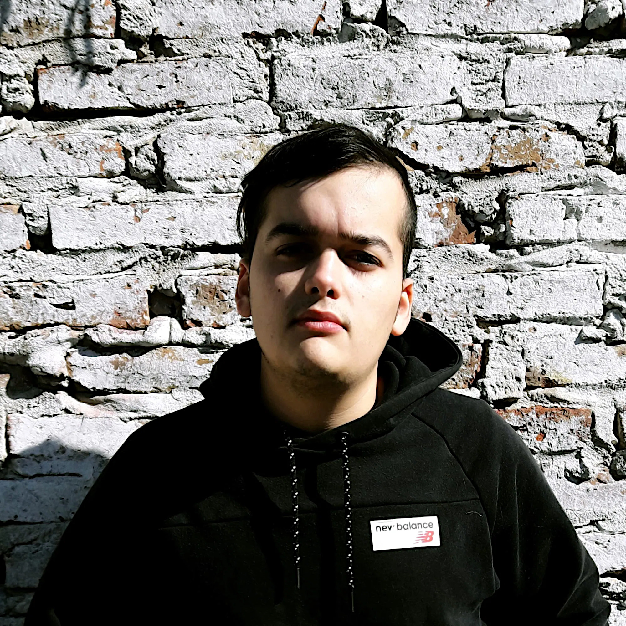Argentinian DJ and producer Cris Rosales standing in front of a brick wall, colour image.