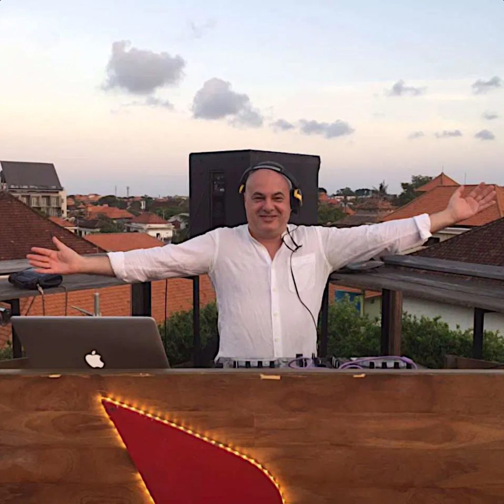 Italian DJ and Producer Marco Mei standing performing on a rooftop in Taiwan with his arms outsretched and smiling at the cameraman, colour image.