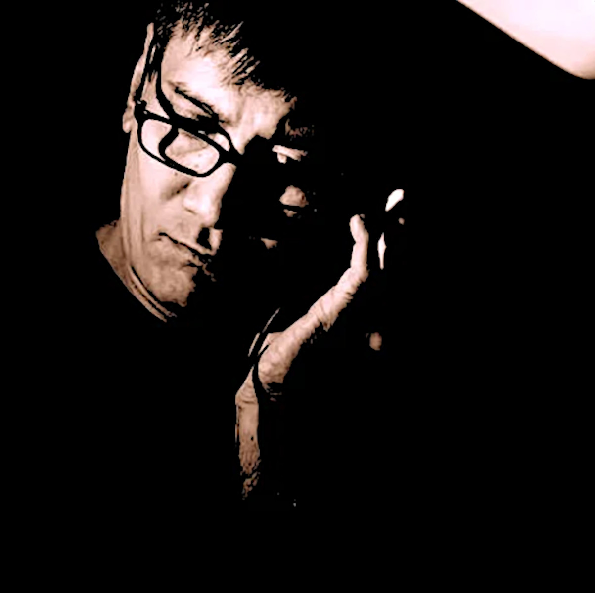 Singaporean DJ and producer Brendon P holding a earphone to his left ear, colour image.