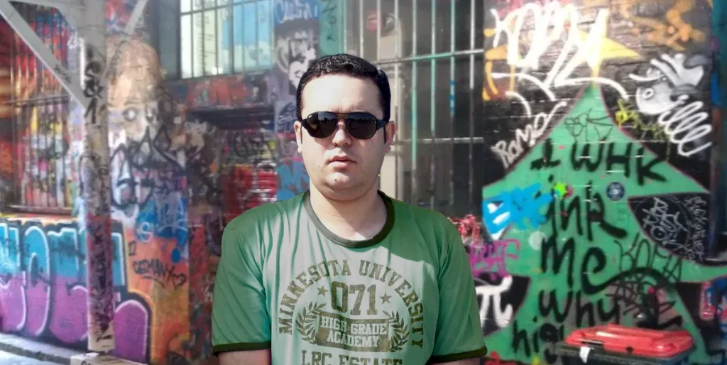 Portuguese DJ Joshua standing in front of a graffiti wall in Melbourne, Australia, colour image.
