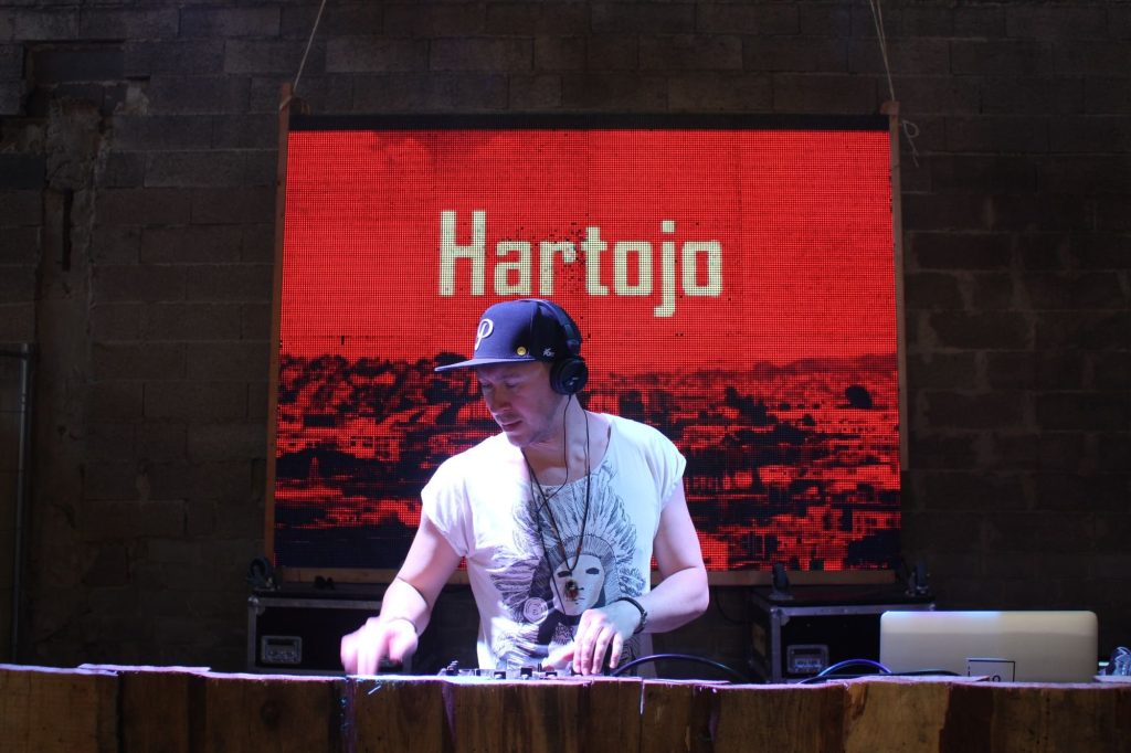 Hartojo (Daniel Wiess) performing on DJ equipment at an event.