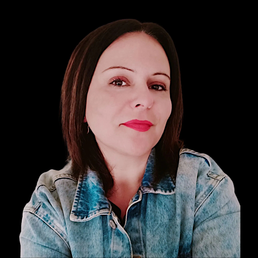 Spanish DJ Ana Wolf smiling at the camera wearing a denim jacket and red lipstick in a colour studio shot with a black background.