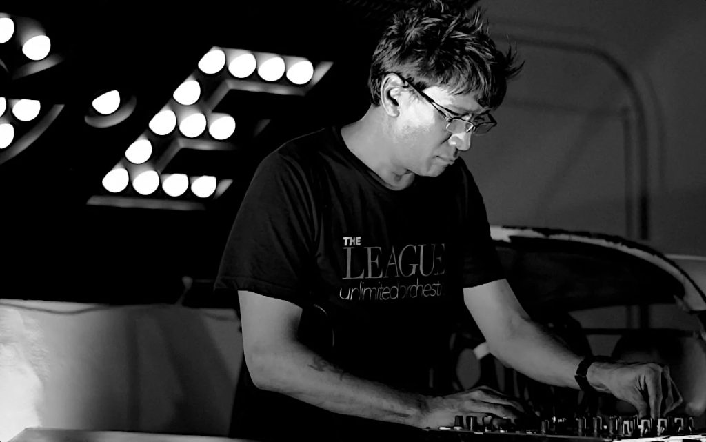 Singaporean DJ and producer Brendon P leaning forward towards mixer whilst performing in upper body shot, black and white image