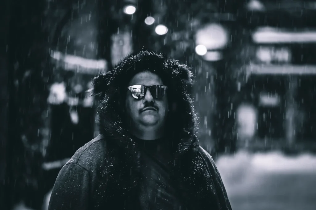Black-and-white portrait of Canadian DJ Spiritual Viking, also known as Trevor Peterson, wearing sunglasses in the snow, representing his Techno sound and Montreal club background.