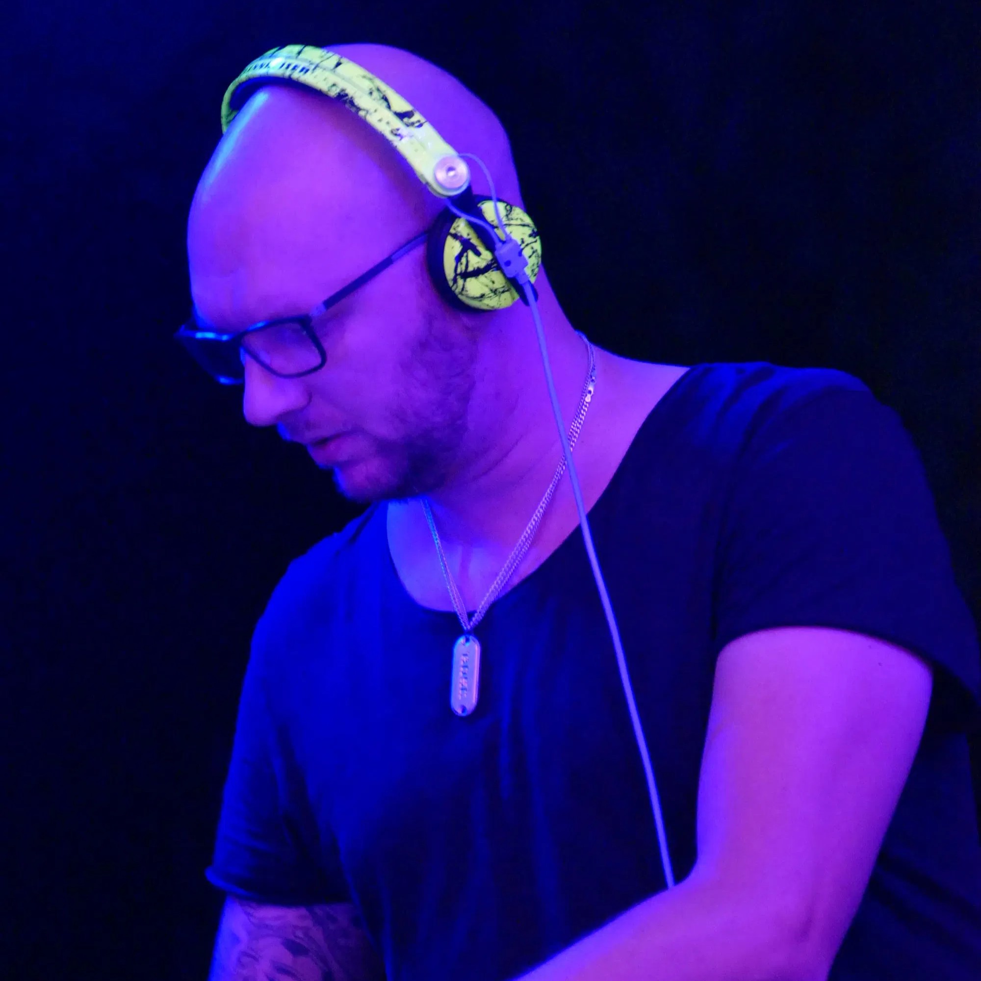 German DJ and producer Whatever Music performing at an event in Germany, wearing headphones and a black t-shirt and his custom Sennheiser headphones, colour image.