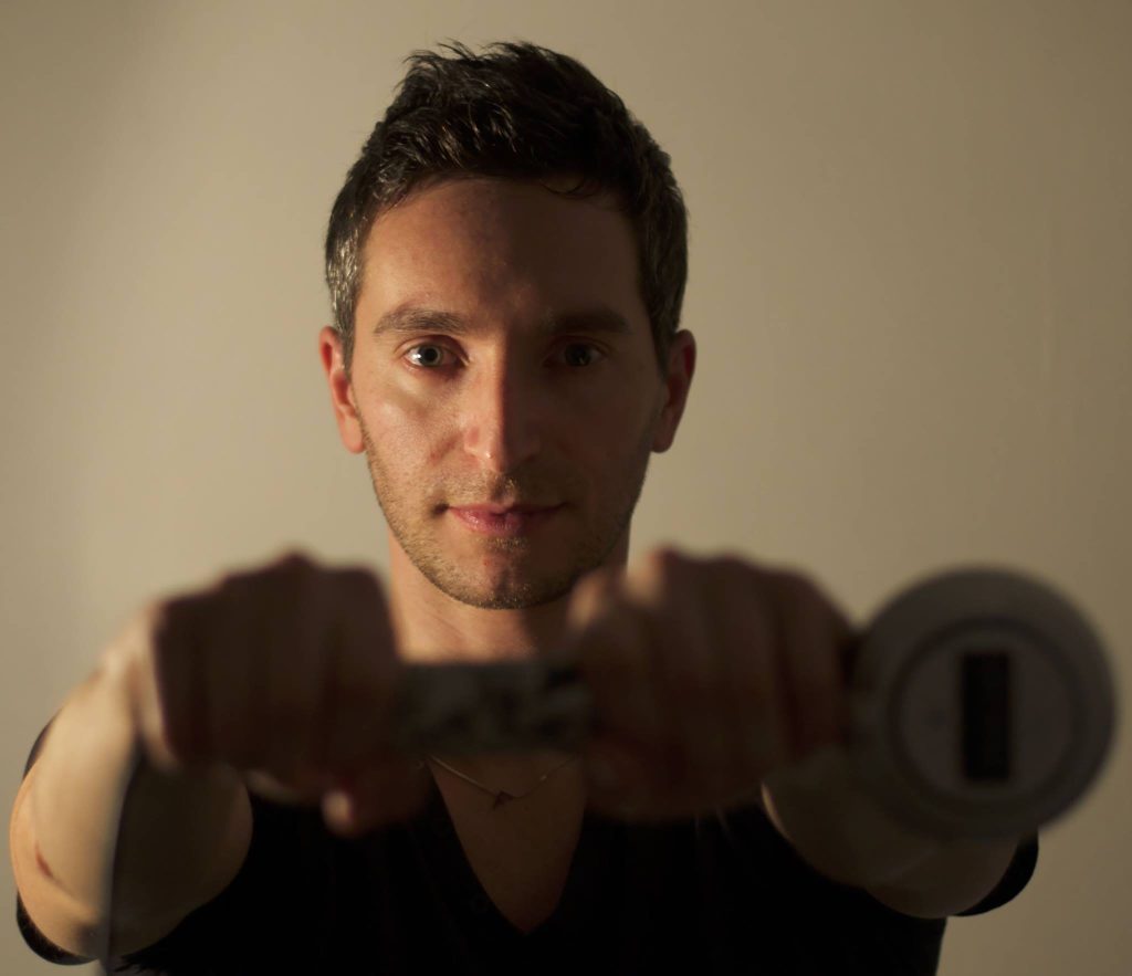 Italian DJ and producer Inve standing holding a monophone in front of him, colour image.