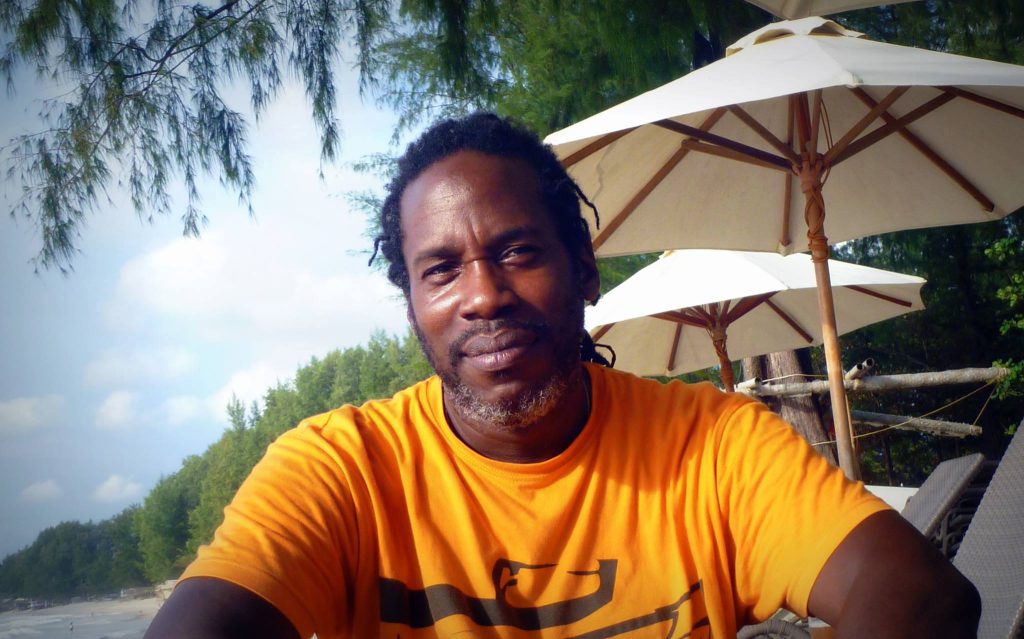 British DJ and producer Bert Bevans sitting on a beach in Bali, colour image.