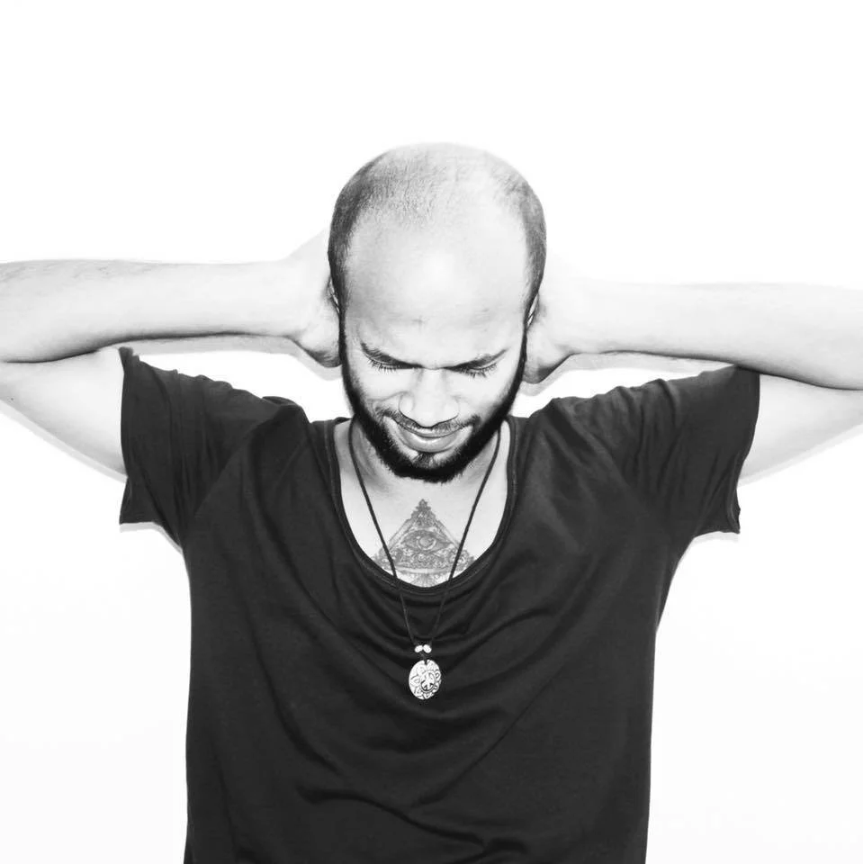 Indian DJ and producer Ethan Bass holding his hands on his ears, black and white image.