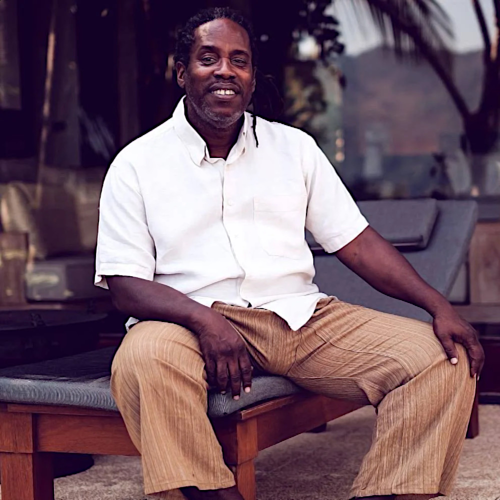 British DJ and producer Bert Bevans sitting on a bench at a holiday resort, colour image.