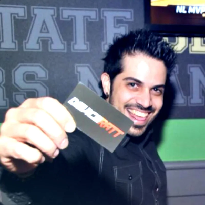 American DJ and producer Jose norat holding up a business card and smiling, colour image.