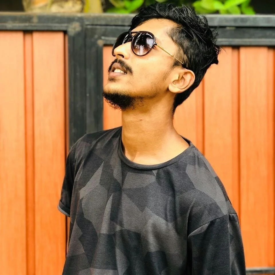 Sri Lankan DJ Darin Zilla wearing sunglasses and looking up to the sky, colour image.