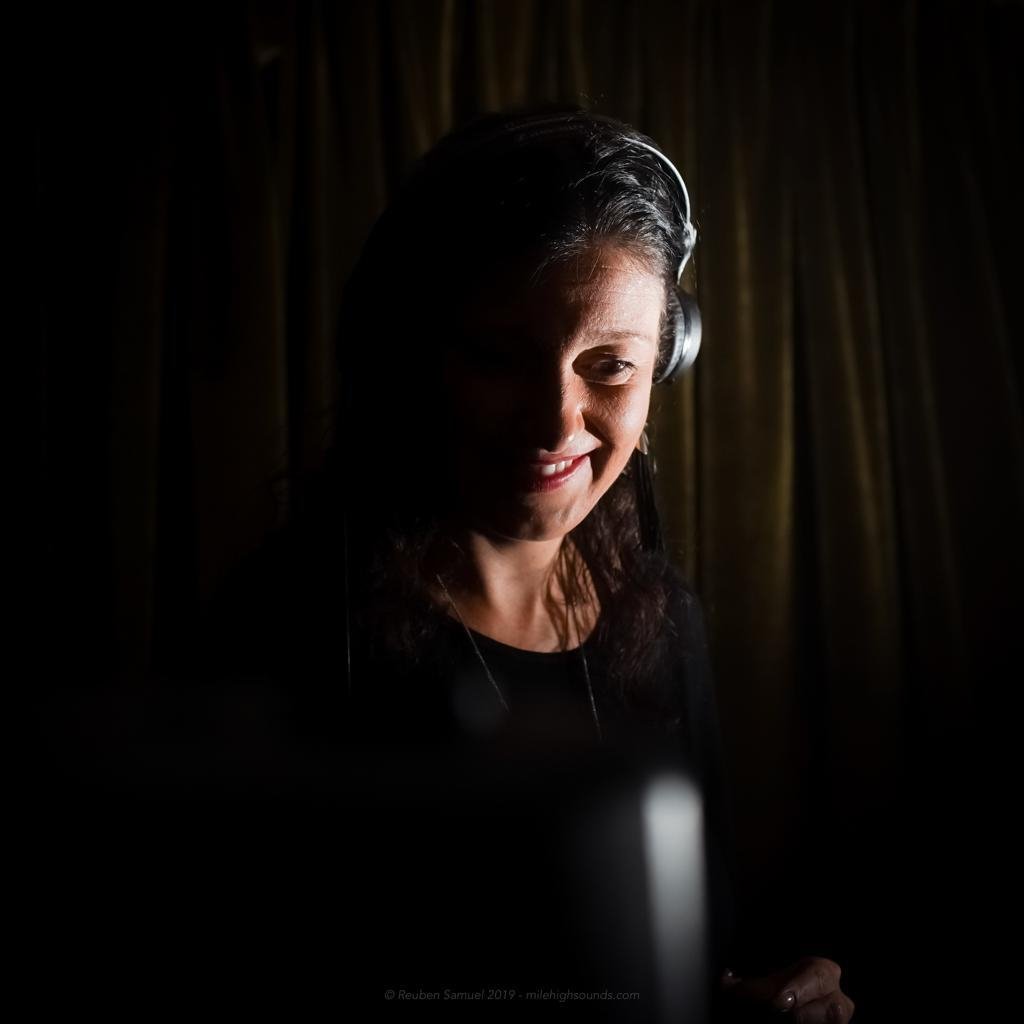 Romanian DJ and producer Biscuit smiling as she performs as a DJ, colour picture with shadowing.