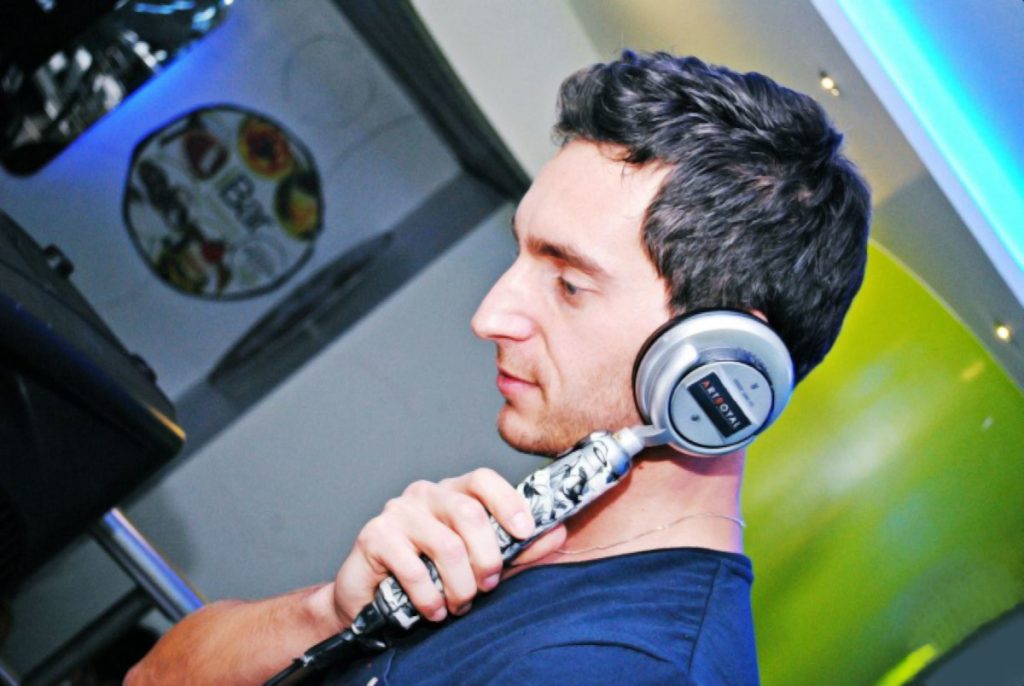 Italian DJ and Producer Inve holding monophone on left ear at iBar, colour image.