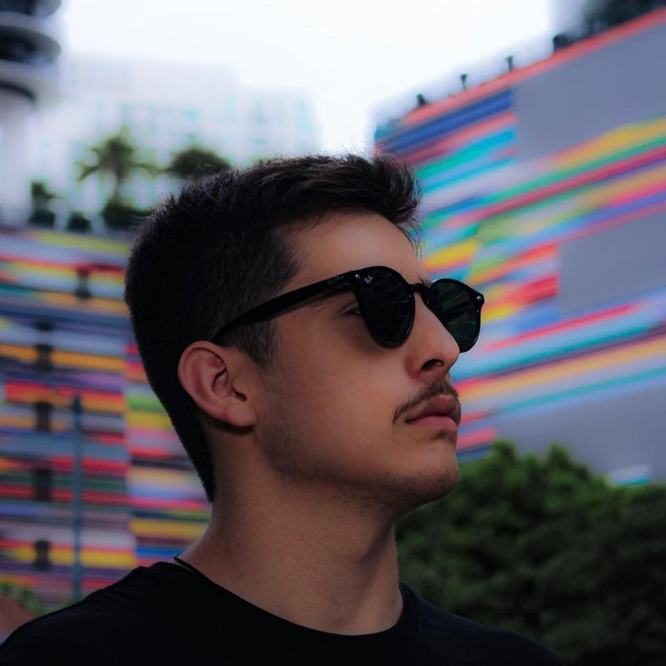 Argentianian DJ and producer Ric Niels headshot with his head turned to the left wearing sunglasses, colour image.