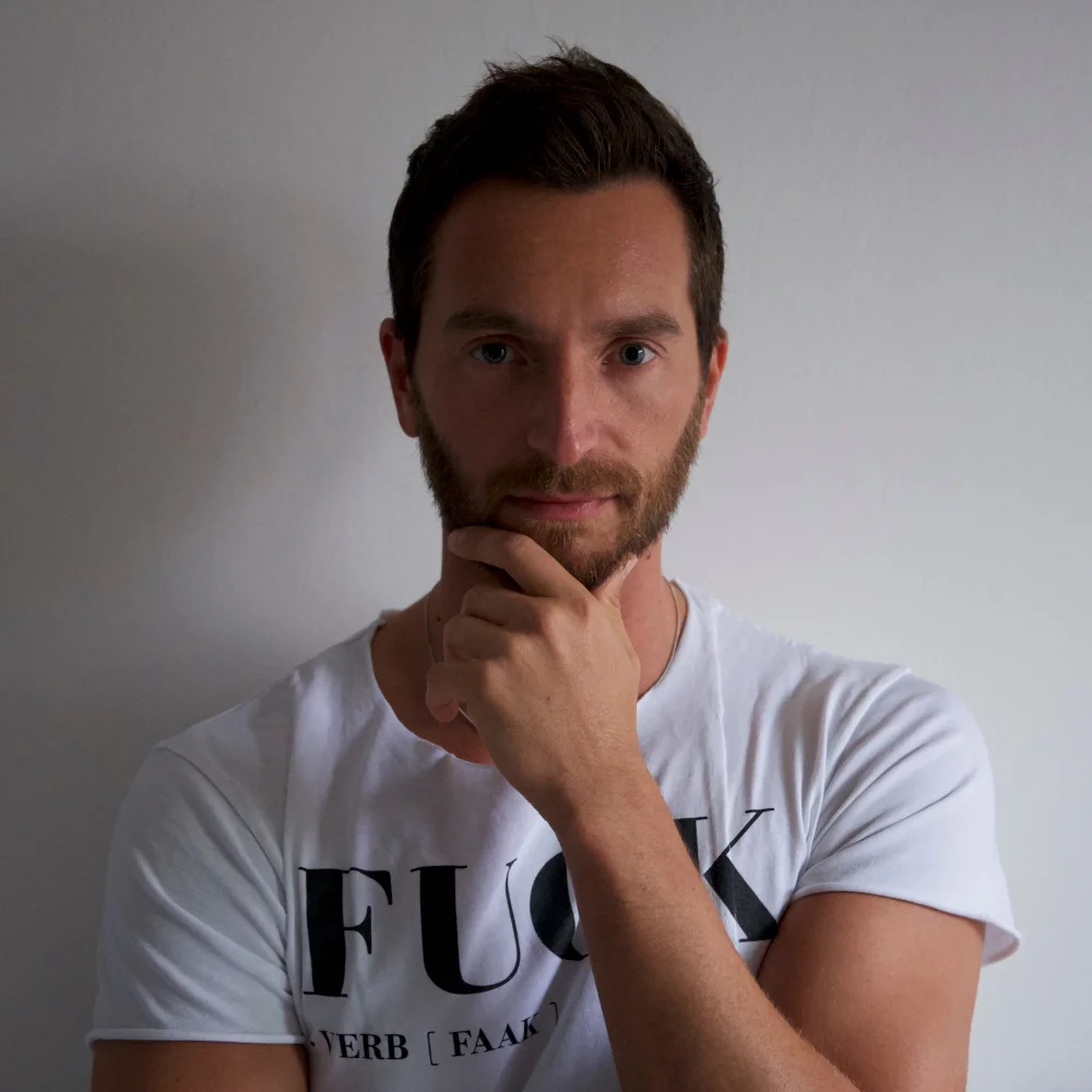 Italian DJ and producer INVE of INVE and Forsi standing looking at camera with his left hand on his chin, colour image.