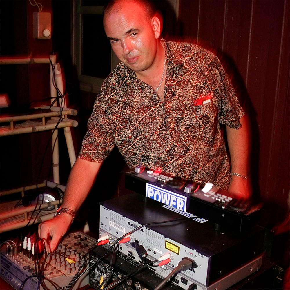 German DJ Nick E. Meta playing with the control on a sound mixer at an event whilst looking at camera, colour image.