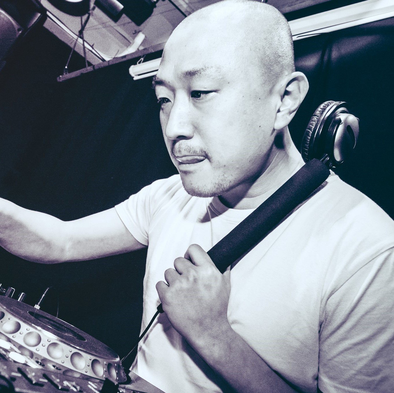 Taiwanese DJ and producer holding a monophone to his left ear whilst performing as DJ, black and white image.