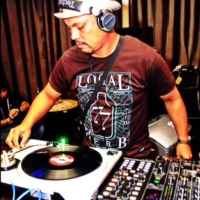Filipino DJ and producer Herb Cabral a.k.a The Herbman performing at a venue on Technics Sl1200 turntables, colour image.