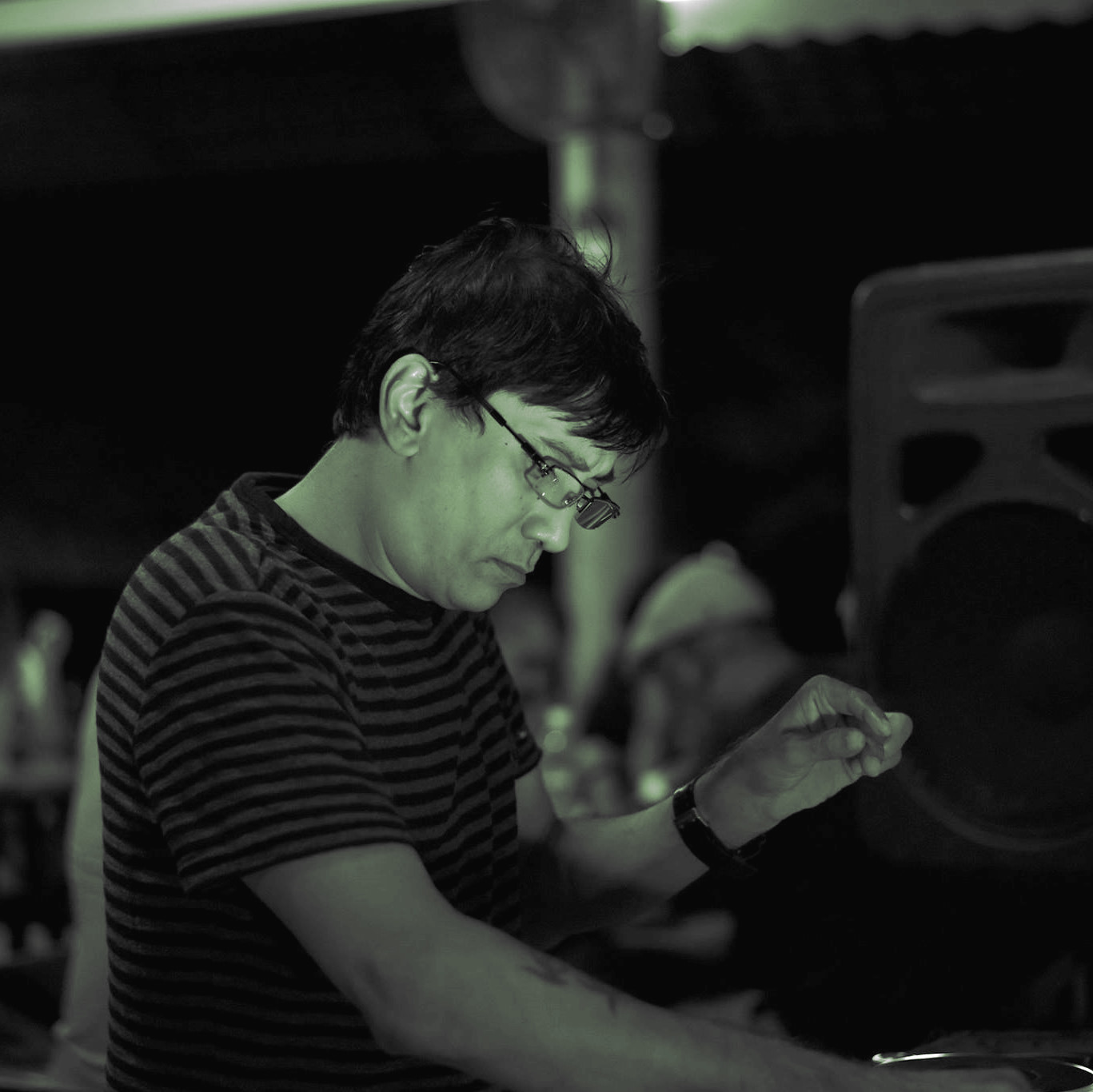 Singaporean DJ and producer Brendon P performing as a DJ at an event in Singapore in a side shot, image is in black and white with a green tinge.