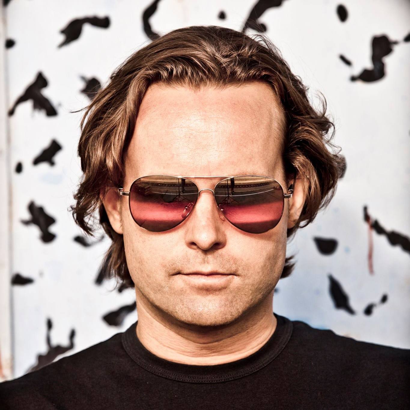 Austrian DJ and producer Chris Colt standing and wearing sunglasses looking directly at camera, head shot in colour.
