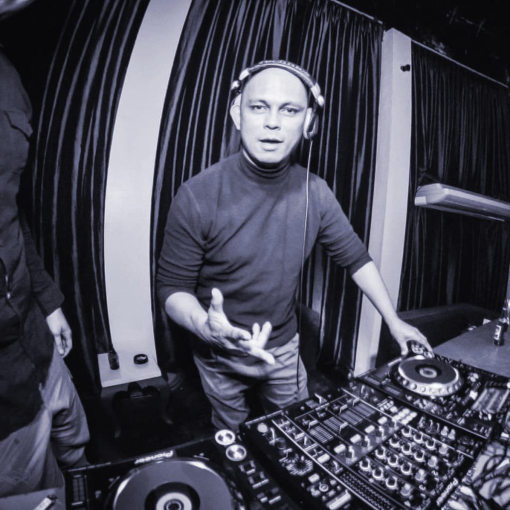 Filipino DJ and producer Herb Cabralperforming as a DJ at The Mansion, black and white image with blue tinge.