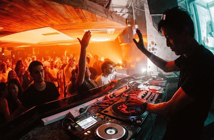 Singaporean DJ and producer Brendon P performing at an event looking out intop the crowd with his right hand raised, colour image.
