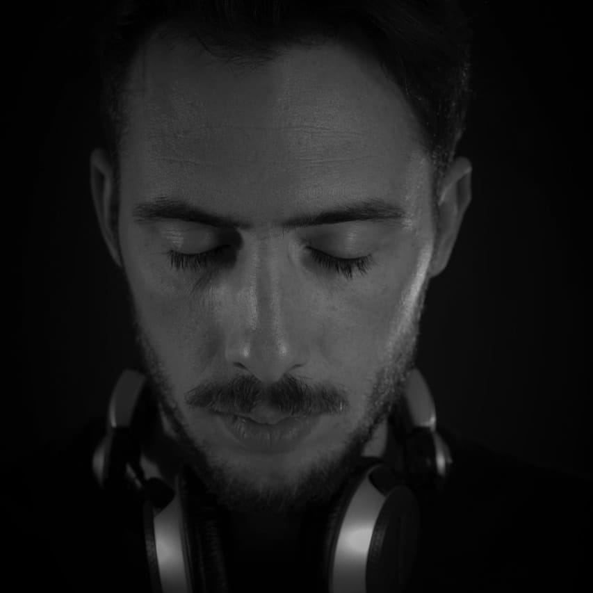 Argentinian DJ and producer Boris Louit head shot wearing headphones around neck with eyes closed, black and white image.