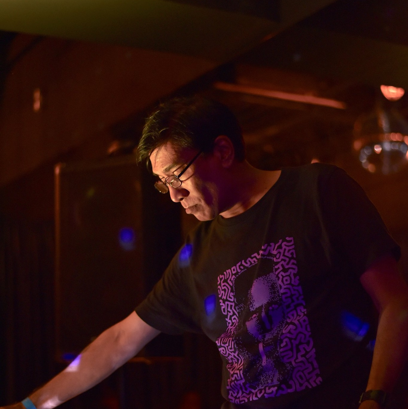Singaporean DJ and producer Brendon P performing as a DJ at an event, side image in colour.