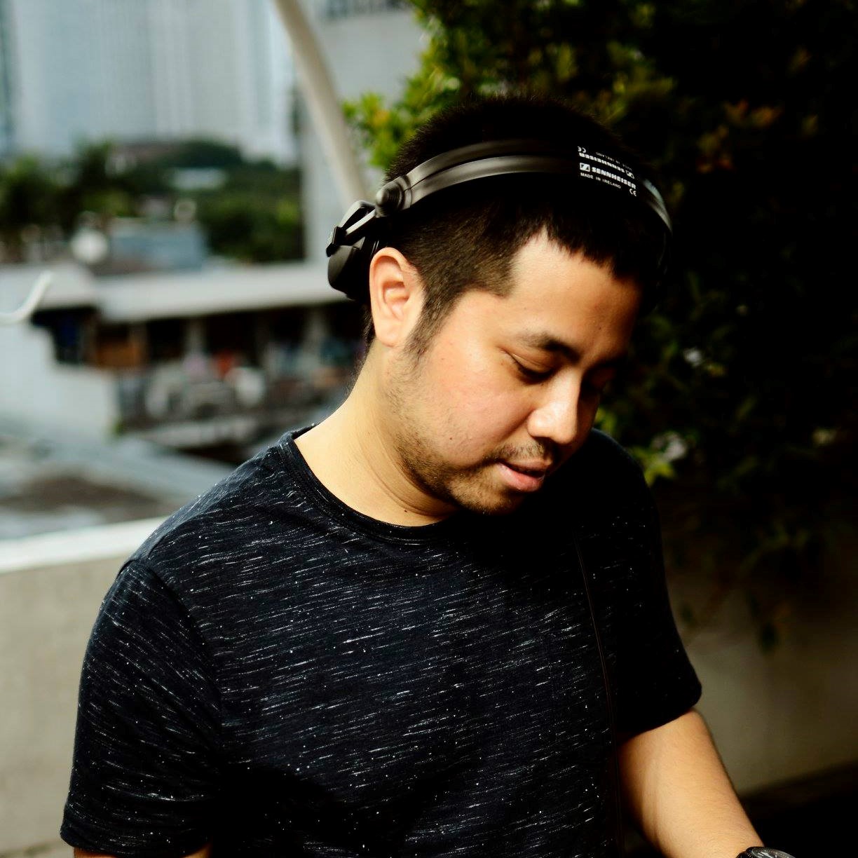 Indonesian DJ Nandiperforming as a DJ with headphones on his head looking down at mixer, colour image.