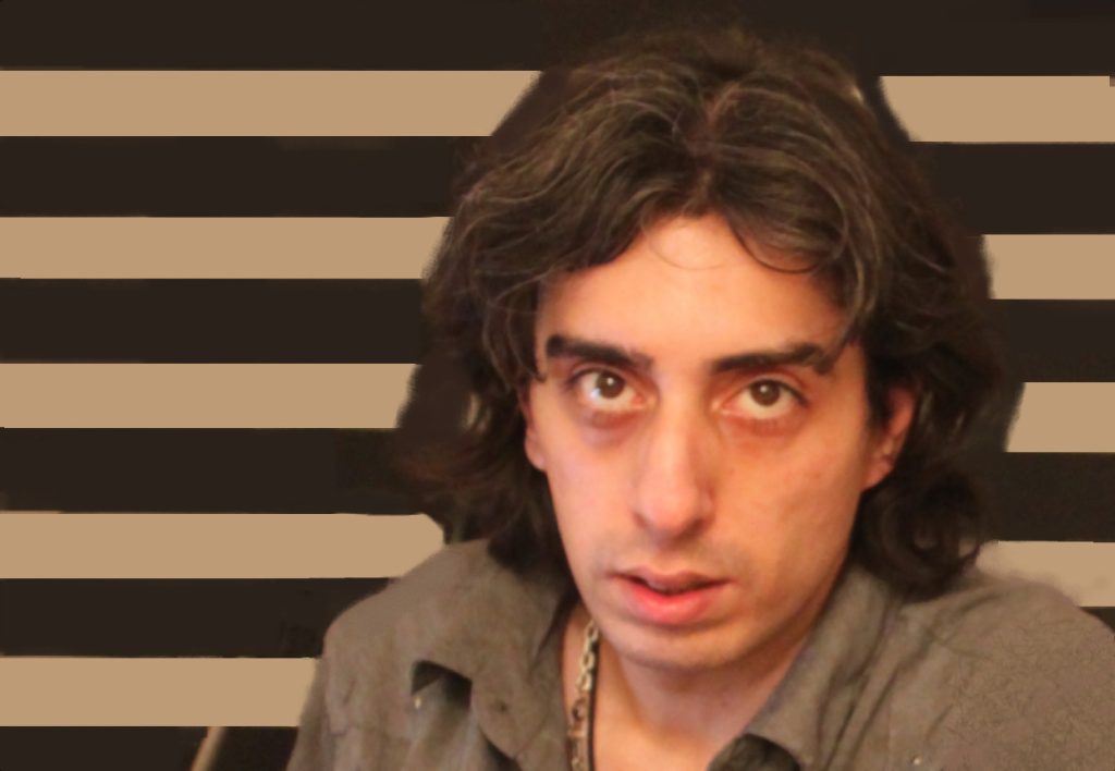 Dadgar with shoulder-length dark hair and a neutral expression, against a striped background.